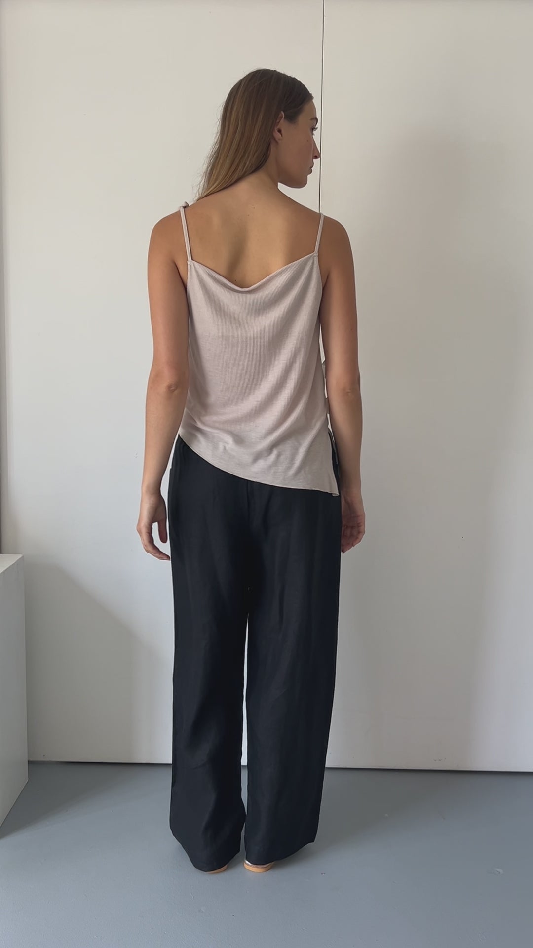 female model wears the split top by Deiji Studios in shell


a sheer fine knit relaxed tank with a fold over cowl neckline and low draping back, features self fabric rouleau straps, baby lock hem finishes and a asymmetric bottom detail


made from a responsible blend of 85% Recycled Polyester and 15% Viscose

paired with a black cotton skirt