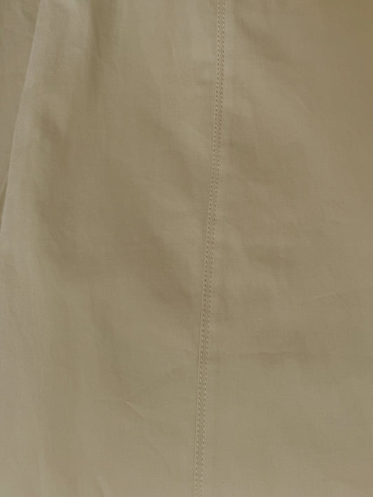 A close-up of the Pocket Pant - Stone by Deiji Studios shows beige organic cotton fabric with a vertical center seam, highlighting its texture and detailed stitching.